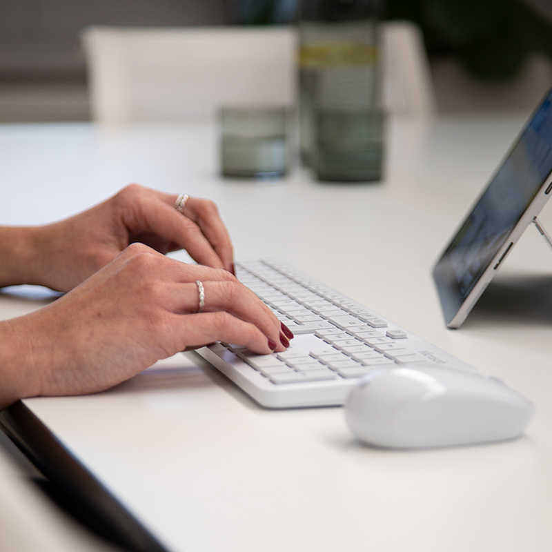 Frau tippt auf Tastatur mit einem Tablet im HomeOffice